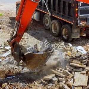 Excavator loads construction waste into of material for disposal from construction a home renovation